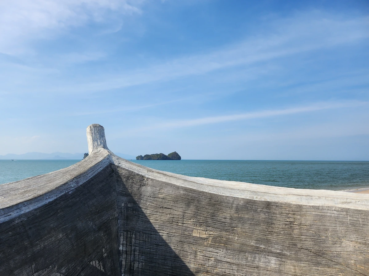 Sea, islands and a boat sculpture on the shore.